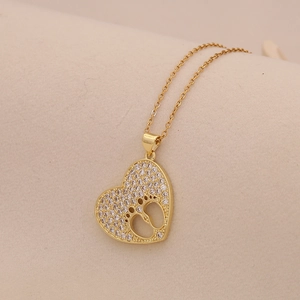 Close-up of golden heart pendant with micro-set zircon and hollow paw print detail