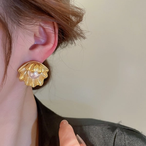 Vintage style gold shell flower earrings with center pearl on a female model