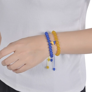 Detail of adjustable blue and yellow beaded bracelets with heart pendant on wrist