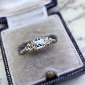 Detalle de anillo de diamante corte esmeralda con borde milgrain en caja terciopelo