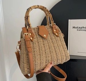 Detail of hand-woven straw box bag featuring natural bamboo handle and premium PU leather strap