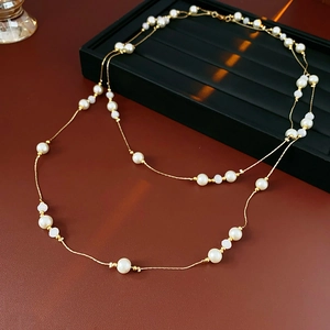 Close-up of double-layer beaded necklace with pearls and gold beads on black tray