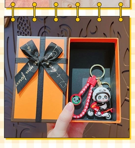 Cartoon panda on motorcycle keychain with red braided lanyard inside an orange gift box