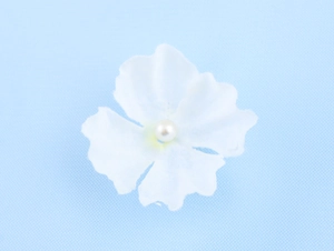 Detail shot of the white 3D fabric flower appliqué with a pearl center on the dress