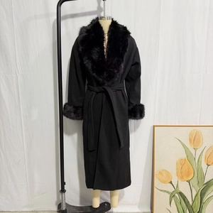 Dettaglio del cappotto lungo nero con grande collo in pelliccia e cintura in vita coordinata
