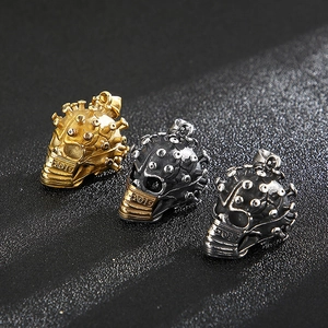 Trois pendentifs tête de mort virus style punk en or, argent et noir sur fond sombre
