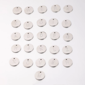 Macro view of 26 polished silver stainless steel alphabet charms arranged in a grid