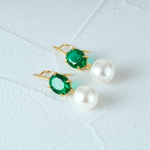 Macro detail of S925 hallmark on gold plated silver earrings with emerald and pearl