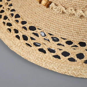 Detailaufnahme von Raffia-Sonnenhut mit dekorativen Holzperlen und Wellen-Webstruktur
