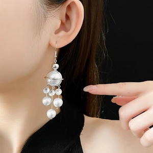 Detail of silver planet drop earrings with pearls and crystals shown on model side profile