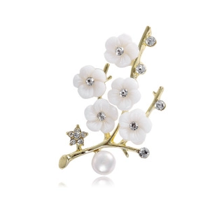 Macro detail of plum blossom brooch with gold branches, white petals and pearls