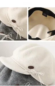 Macro detail of wool beret with metal heart pendant and CLLINE brand emblem