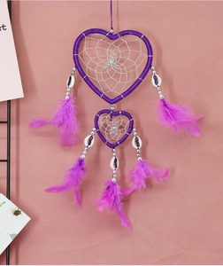 Detail of a purple heart-shaped dreamcatcher with feathers, shells, and silver beads