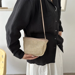 Borsa a secchiello minimalista in paglia intrecciata beige con un outfit casual moderno