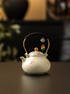Detail of ceramic teapot with golden handle, brown rope wrap and floral patterns