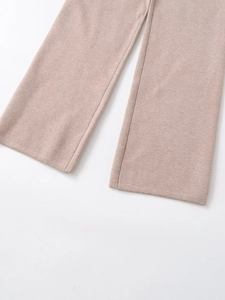 Detailed macro view of knitted khaki wide-leg trousers showing texture and hemline finish