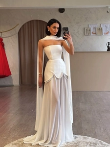 Detail of elegant white strapless dress featuring pearl waist trim and a sheer chiffon cape