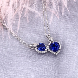 Macro detail of two heart-shaped blue sapphire pendants with silver chains and tiny diamonds