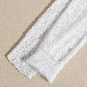 Close-up of white lace fabric with intricate mesh patterns and floral embroidery details