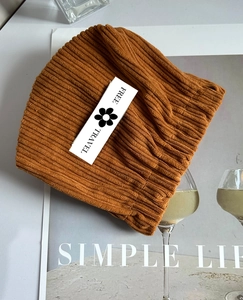 Detailed close-up of brown corduroy cosmetic pouch featuring a Free Travel flower tag