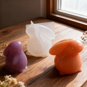 Macro detail of Easter bunny silicone mold with finished resin candles on wood surface
