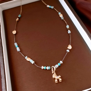 Detail of beaded puppy necklace with blue stones and a zircon gold dog charm