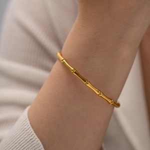 Bracelet jonc bambou en acier inoxydable doré 18K porté sur le poignet d'un mannequin