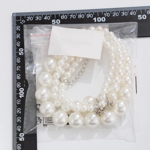 Detailed view of layered faux pearl necklace with silver lobster clasp on a measuring mat