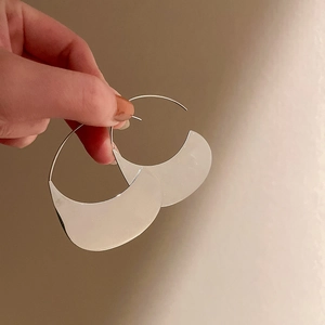 Macro shot of silver crescent earrings with minimalist design and polished finish