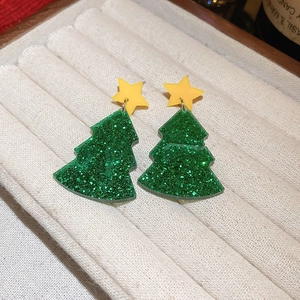 Detailed view of green Christmas tree earrings with glitter and yellow star studs