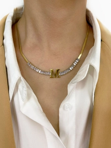 Detail of 18K gold letter M necklace with zircons and sleek flat snake chain on a model