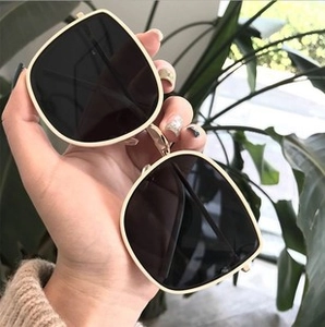 Close-up of square oversized cycling sunglasses with beige frame and dark tinted lenses