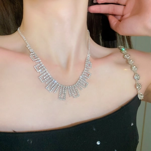 Close-up of sparkling silver tassel necklace with geometric rhinestone links on woman neck