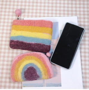 Close-up of rainbow felt coin purses in rectangular and semi-circle shapes on a pink cloth