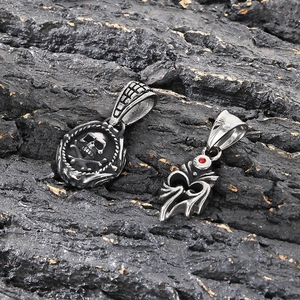 Detailed shot of punk style steel skull pendant and flame charm with red gemstone inlay