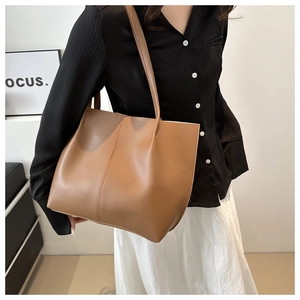 Detail of a brown PU leather tote bag showing side stitching and slim shoulder straps