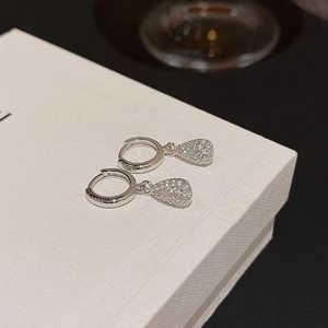 Detail of silver water-drop earrings with pavé-set zircons on a white gift box