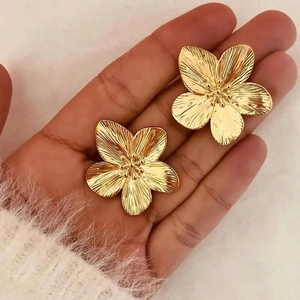 Handheld view of elegant gold five-petal flower earrings with metallic brushed texture