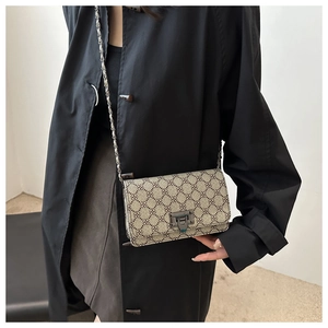 Detail of leopard print shoulder bag with metal chain strap and flap lock on a model