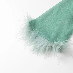 Vue détaillée de la manche en maille verte scintillante avec bordure en plumes