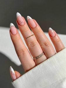 Detail of almond-shaped French press-on nails with white V-tips and silver glitter accents