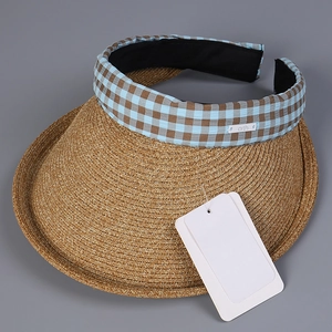 Detail of a straw sun visor with blue checkered trim and metal logo label on the headband