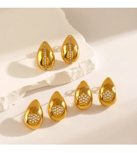 Détail de boucles d'oreilles goutte dorées serties de zircons en étoile, cœur et barre