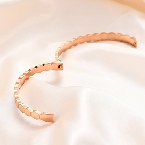 Detail view of rose gold wave bangle open hinge mechanism on white satin background