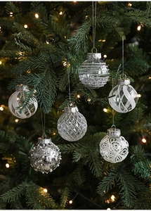 Close-up of silver and white Christmas tree ornaments with glitter and faceted textures