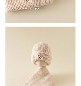 Close-up of baby knitted beanie featuring a brown heart embroidery detail and soft wool texture