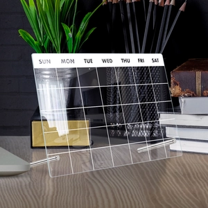 Close-up of a clear acrylic weekly planner with silver metal stands on an office desk