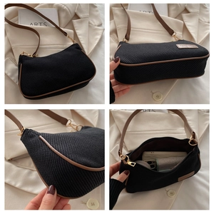 Detail view of black canvas underarm bag with brown leather trim and interior capacity