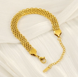 Detail of gold woven stainless steel bracelet with lobster clasp on silk fabric