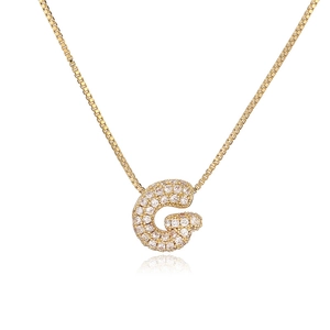 Macro shot of gold bubble initial G pendant with clear cubic zirconia on a box chain
